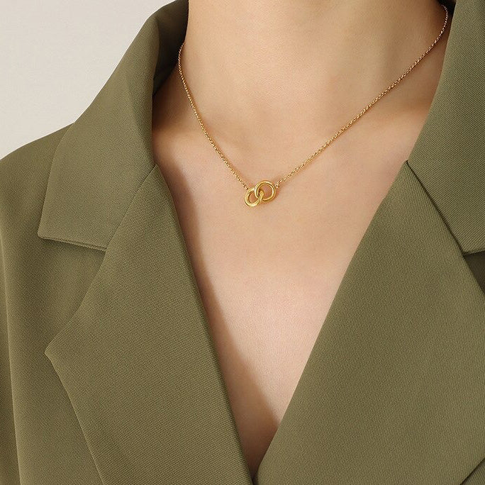 A Gold Double Link Ring Chain Necklace worn on a woman's neck with a green jacket.