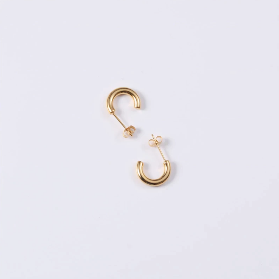 Gold Geo C Earrings shining brightly on a white surface.