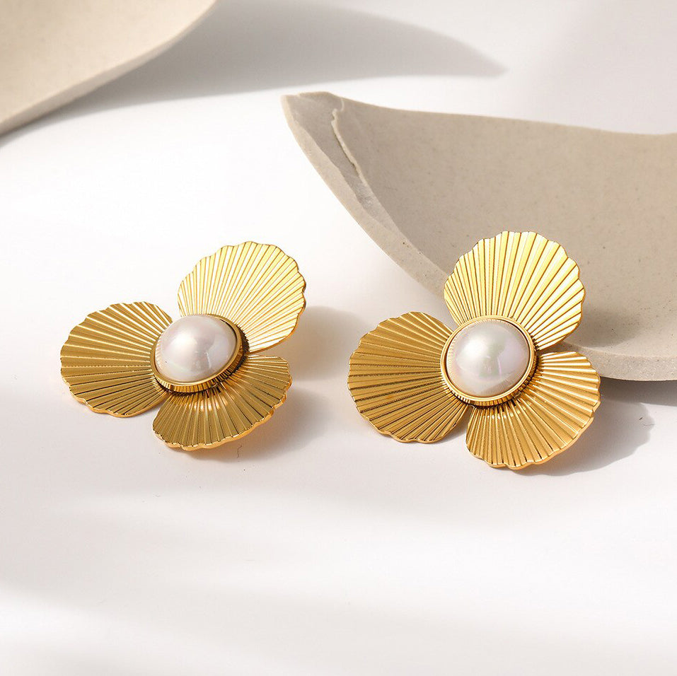 Gold Pearl Flower Earrings laying on a smooth ceramic surface.
