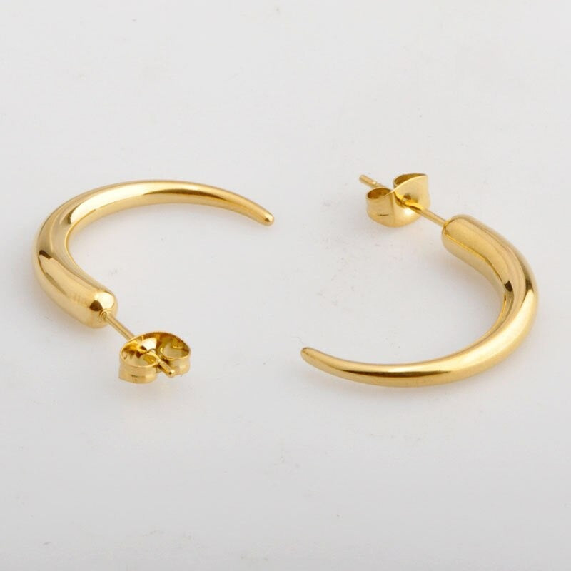 Gold Pipa Chilli Earrings laying on a smooth white surface shining radiantly..