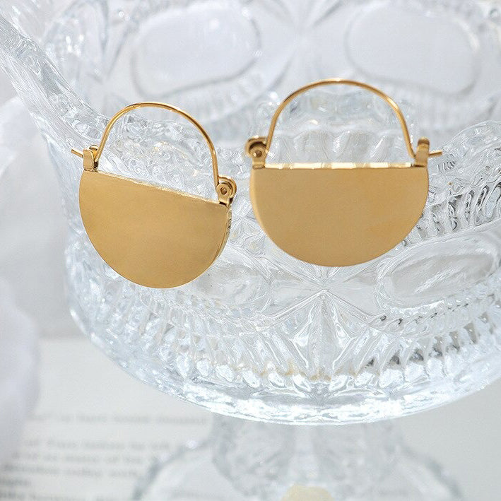 Gold Semi Circle Earrings hanging on a crystal bowl.