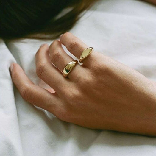 A woman's hand wearing two elegant gold minimalist signet rings.