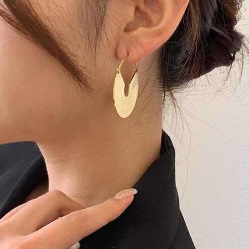 Gold Smooth Fan Drop Earrings being worn by a woman with dark hair.