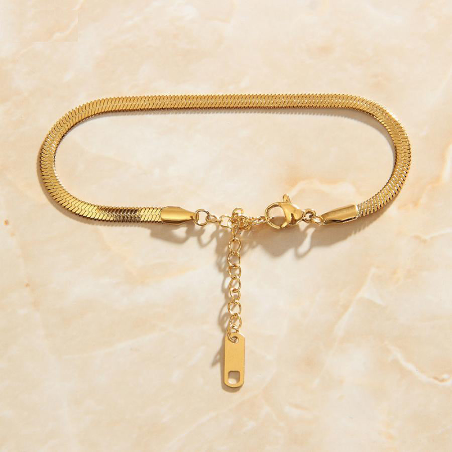 Beautiful Gold Snake Chain Link Bracelet shining brightly laid on top of a smooth pink quartz background.