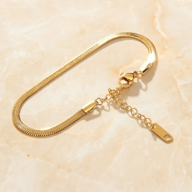 Beautiful Gold Snake Chain Link Bracelet shining brightly laid on top of a smooth pink quartz background.