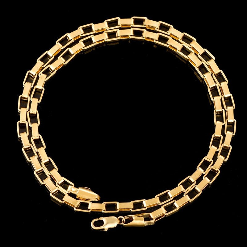 Gold Square Box Chain Necklace coiled on a plain black background.