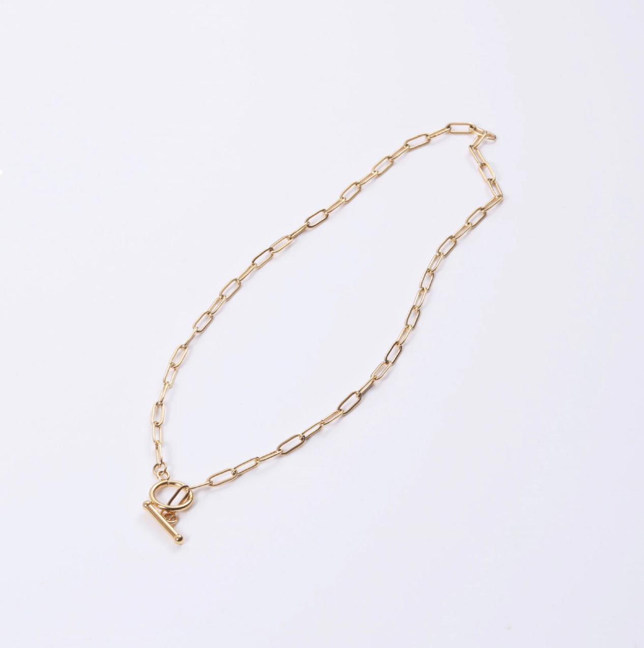 Classic T-bar minimalist necklace laying on a white background surface.