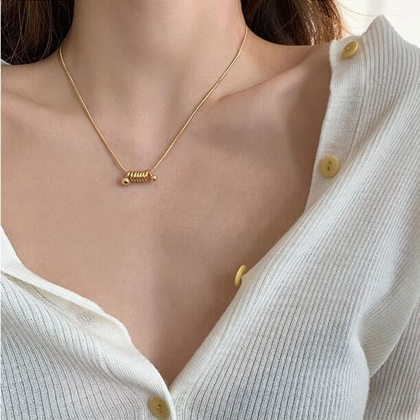 A beautiful gold ball spring necklace worn on a woman's neck.