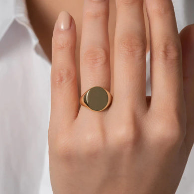 A woman's hand with a gold signet ring, showcasing elegance and sophistication.