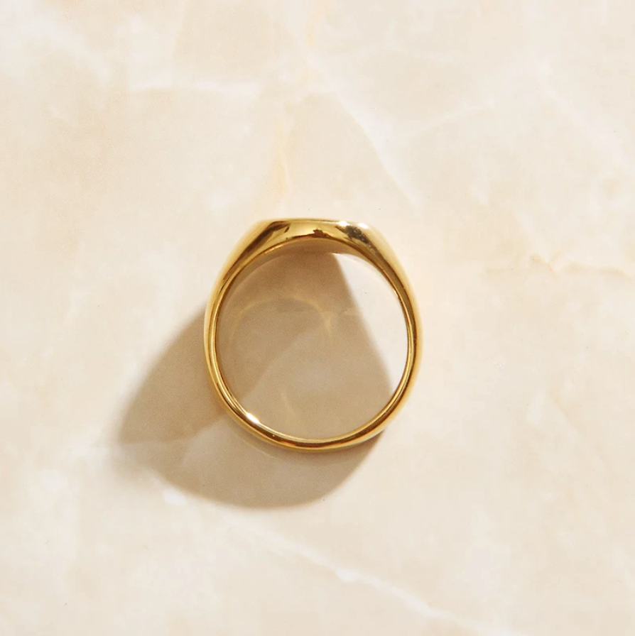 A shiny gold ring resting on a smooth marble surface.