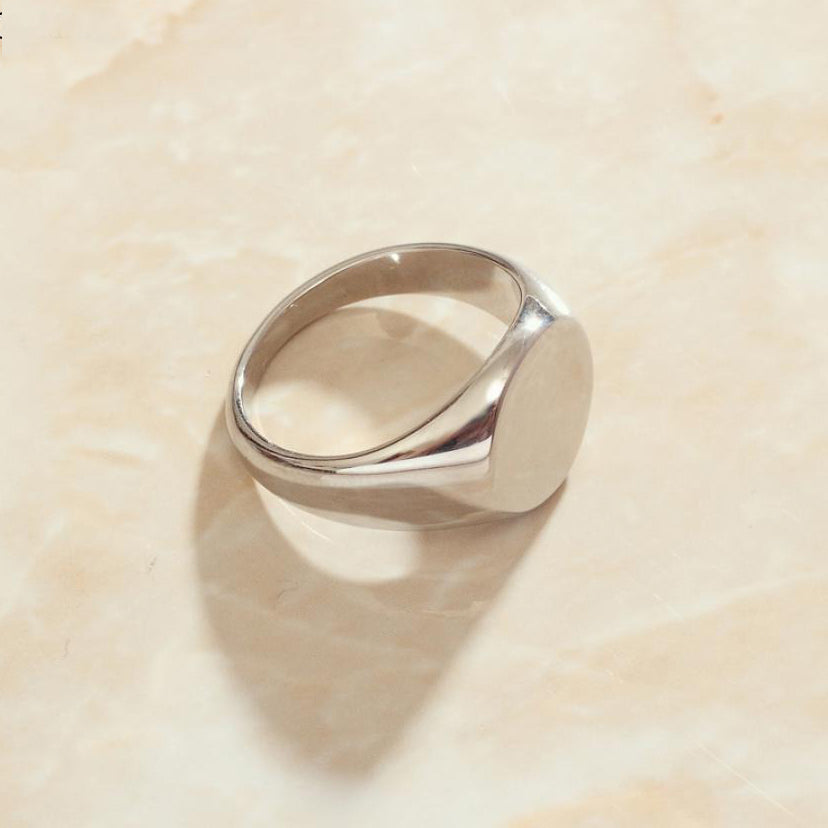 A custom silver signet ring with a round face perfect for custom engravings.