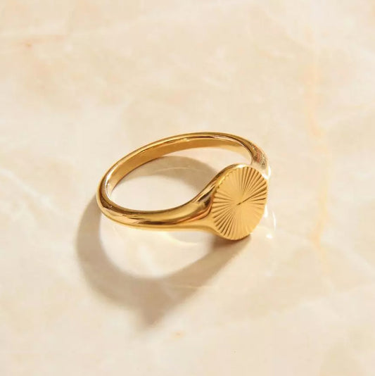 A gold ring featuring a sun design, perfect for adding a touch of elegance and style to any outfit.