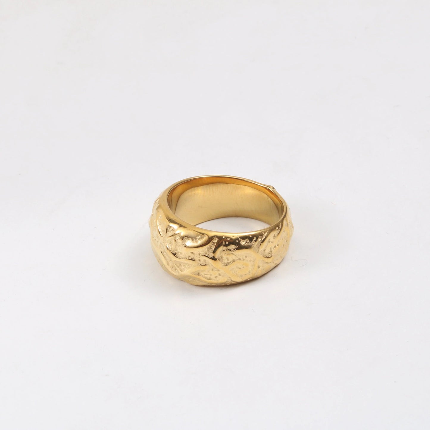 A Gold Walnut Signet Ring shining brightly on a white surface.