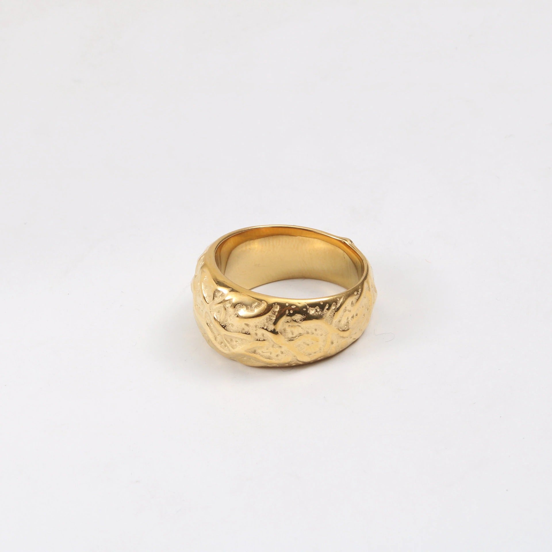 A Gold Walnut Signet Ring shining brightly on a white surface.
