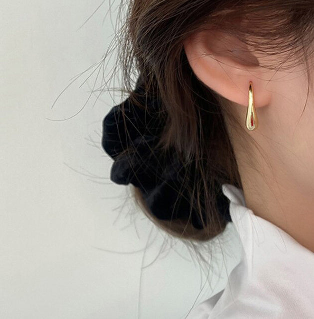 Gold Curved Droplet Earrings worn by a woman with brunette hair.
