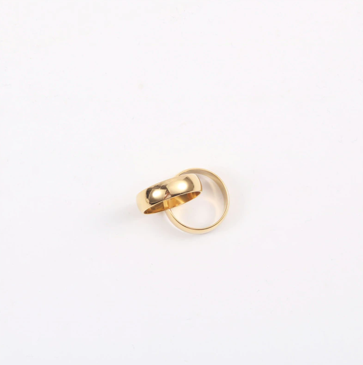 A shiny gold ring resting on a smooth white surface.