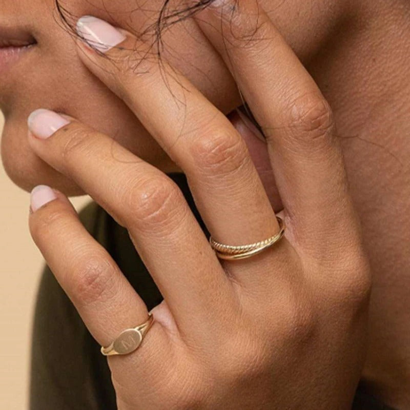 A woman wearing gold interlinked ring wearing nail polish.