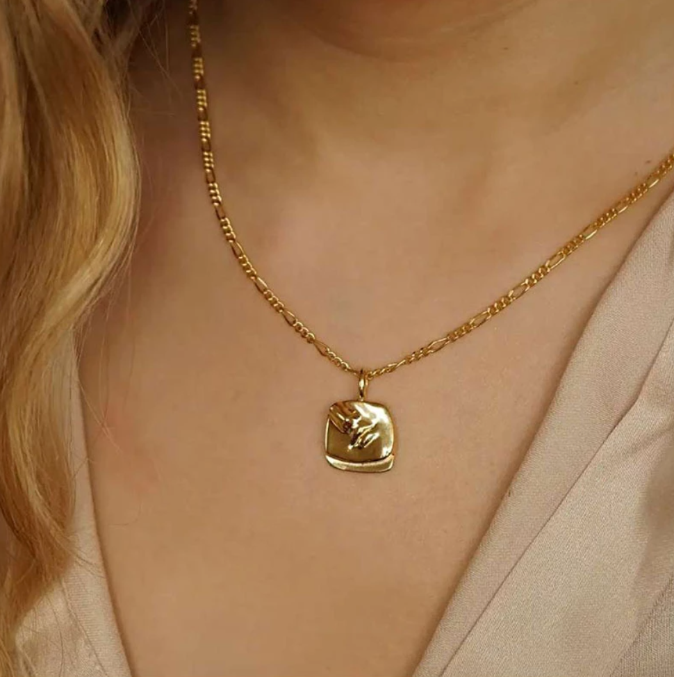 A beautiful Gold Femme Face Pendant Necklace worn on a blonde woman's neck.