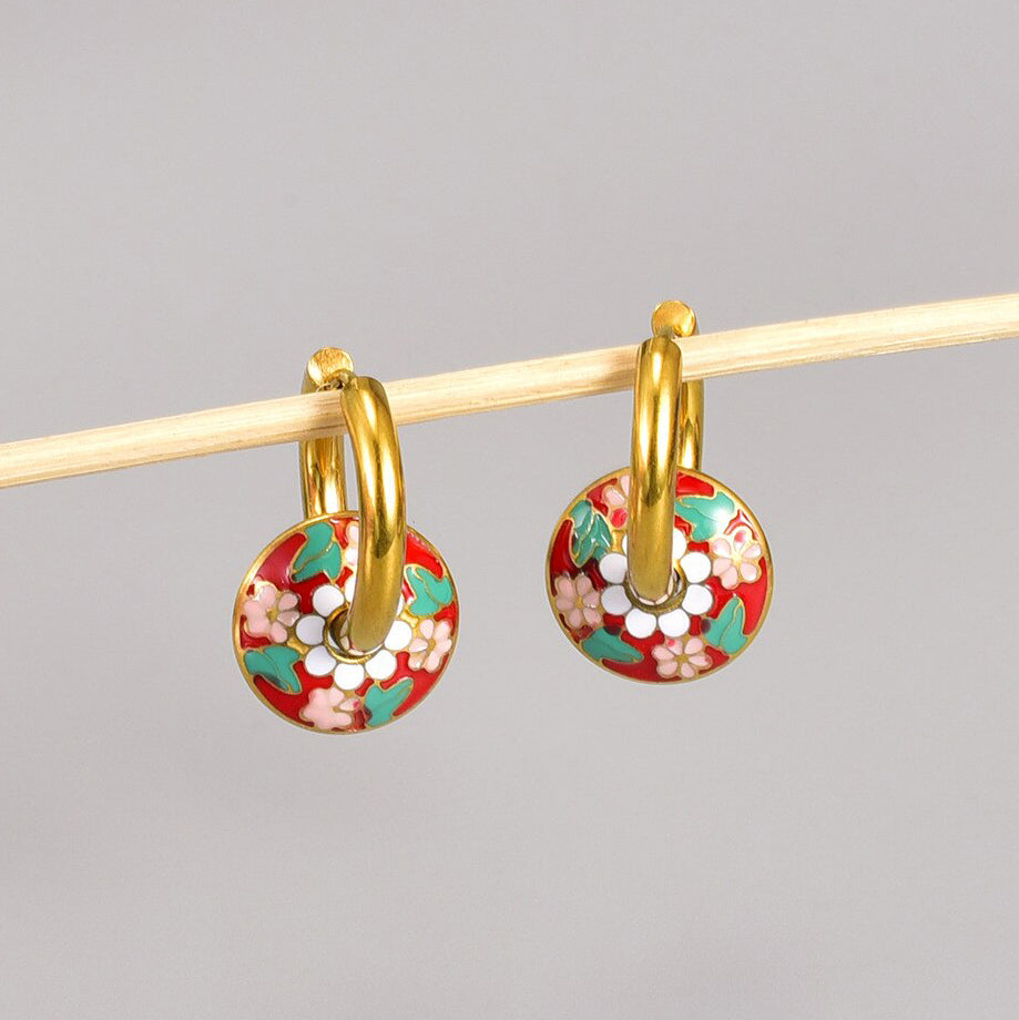 Gold Floral Enamel Loop Earrings hanging on a grey background showing the bright colours of the floral design.