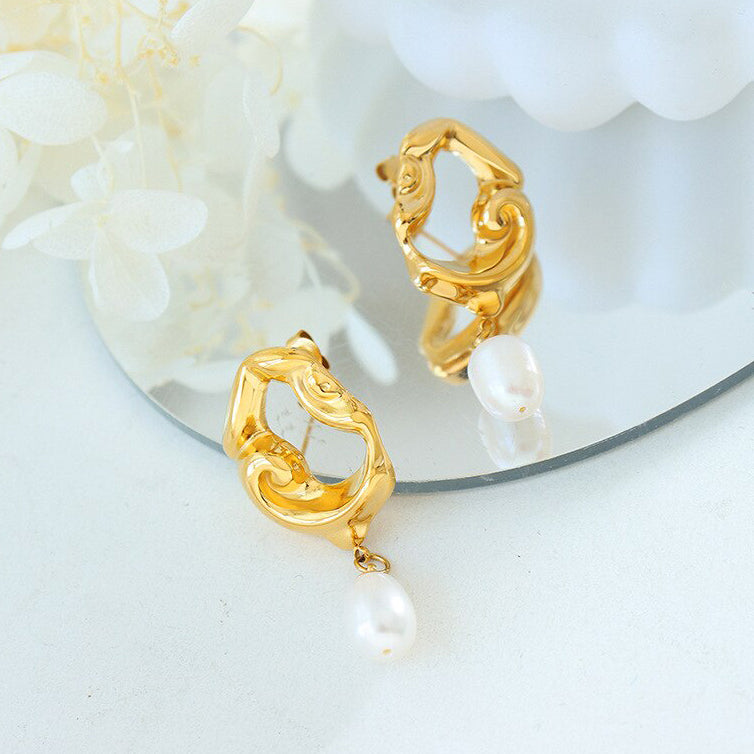 Gold Drop Earrings with Freshwater Pearls laying mirror surface.