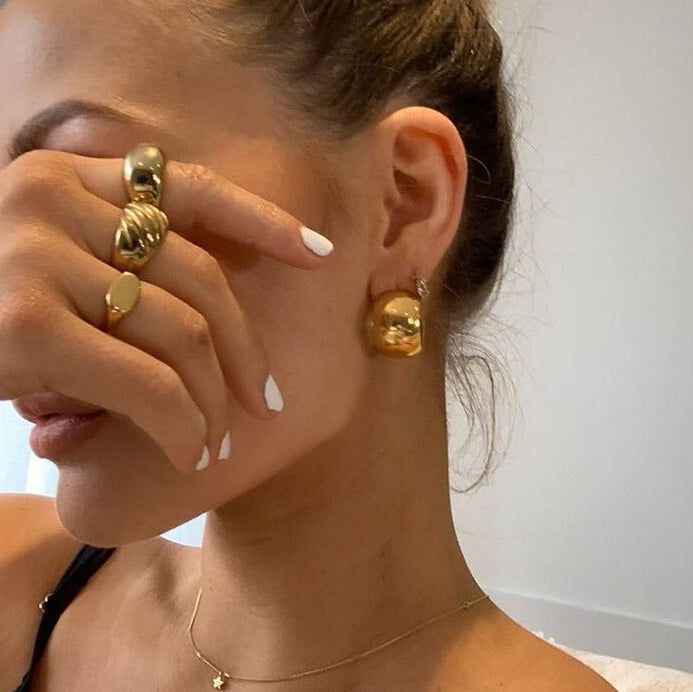 Gold Wide Curved Earrings being worn by a woman with blonde hair.