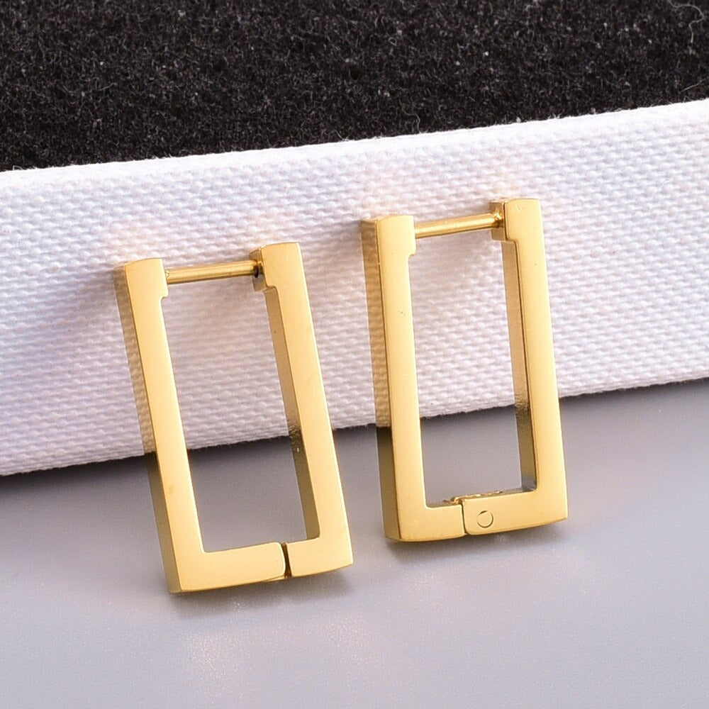 Gold Geometric Rectangle Earrings leaning on a white textured surface.