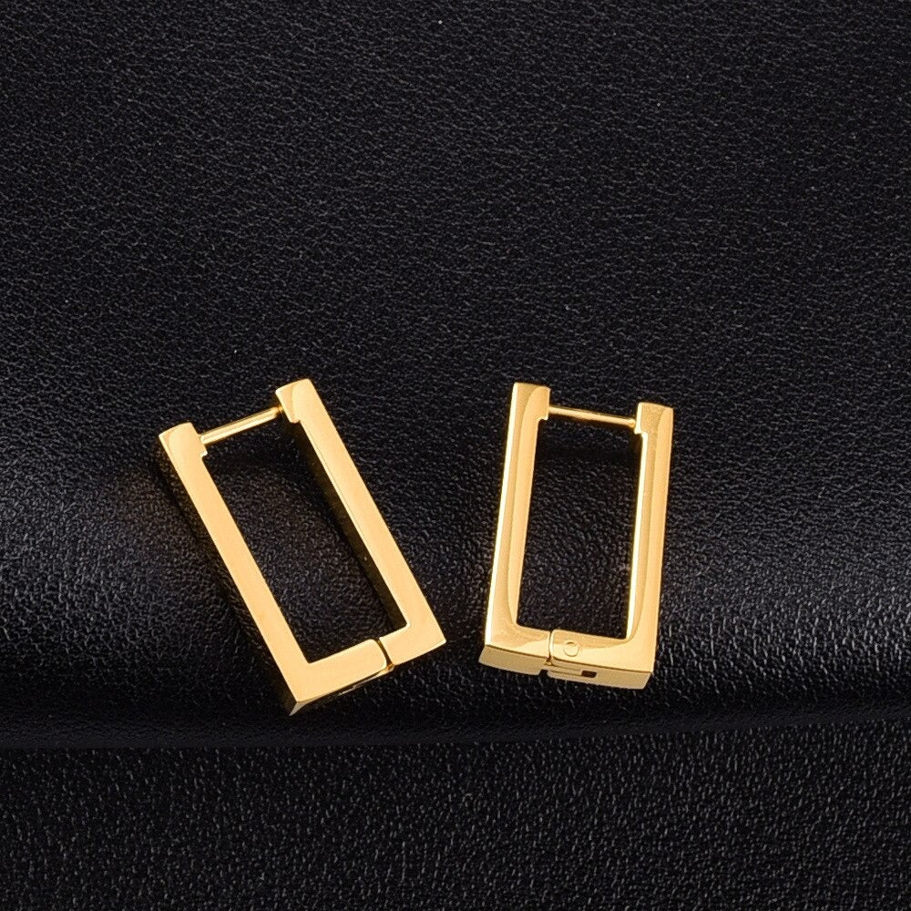 Gold Geometric Rectangle Earrings laying on a black leather surface.