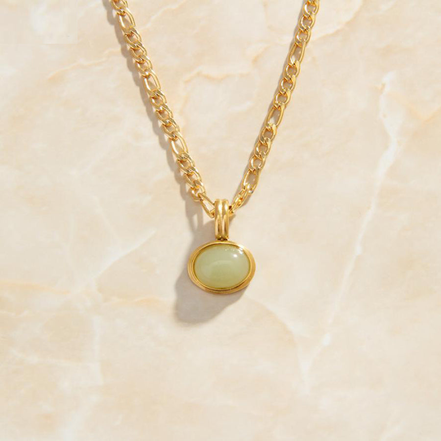 Gold Green Stone Set Pendant Chain Necklace sitting on a marbled background bathed in sunlight.