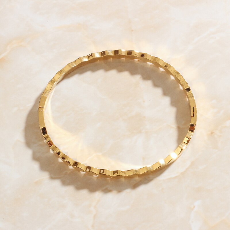 Gold Hexagonal Honeycomb Bangle Bracelet on pink marble background.