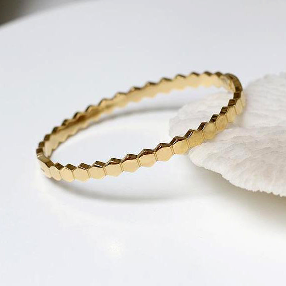 Gold Hexagonal Honeycomb Bangle Bracelet on white surface.