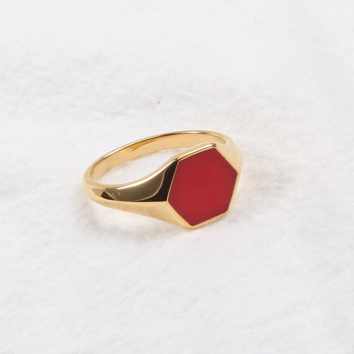 Gold Red Hexagon Signet Ring shining brightly and resting on a white surface.