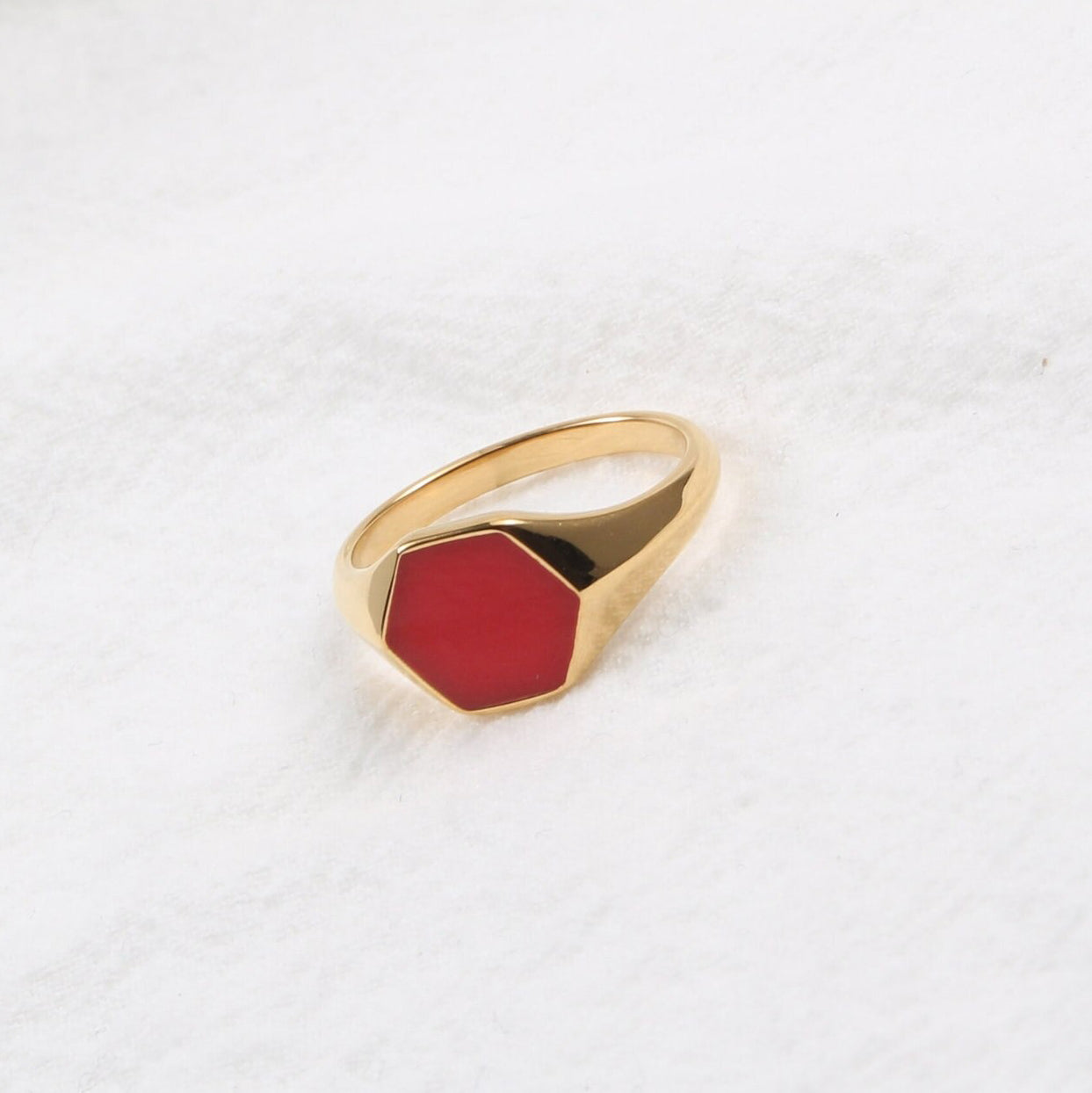 Gold Red Hexagon Signet Ring shining brightly and resting on a white surface.