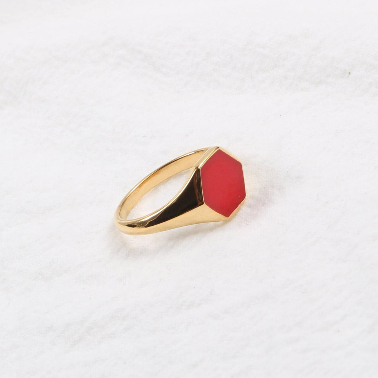 Gold Red Hexagon Signet Ring shining brightly and resting on a white surface.