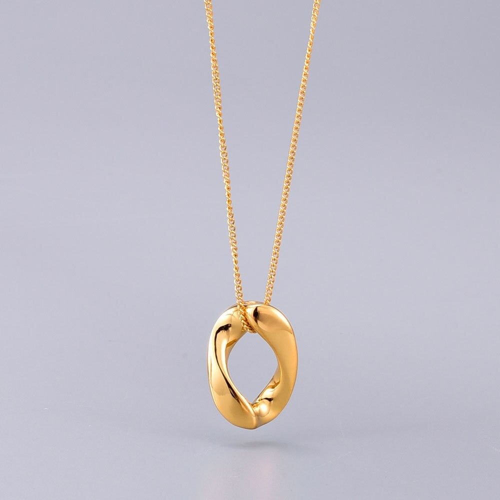 A Gold Infinite Loop Pendant Necklace hanging above a neutral light grey background with a small shadow under the pendant.