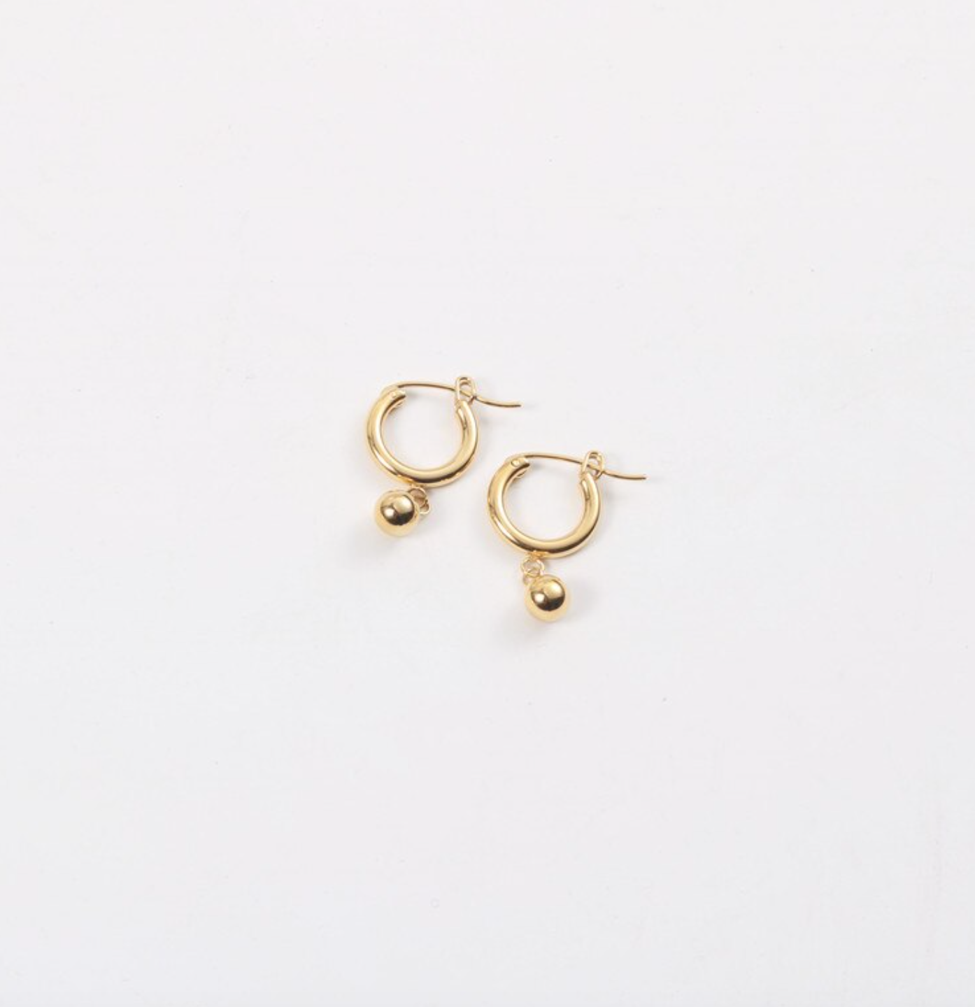 Gold Loop Bead Earrings laying on a smooth white surface.