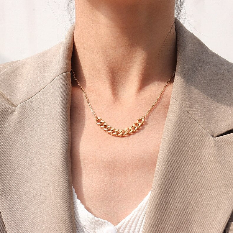 A minimal Gold Mid Chain Necklace worn on a woman's neck with a tan overcoat and white top.