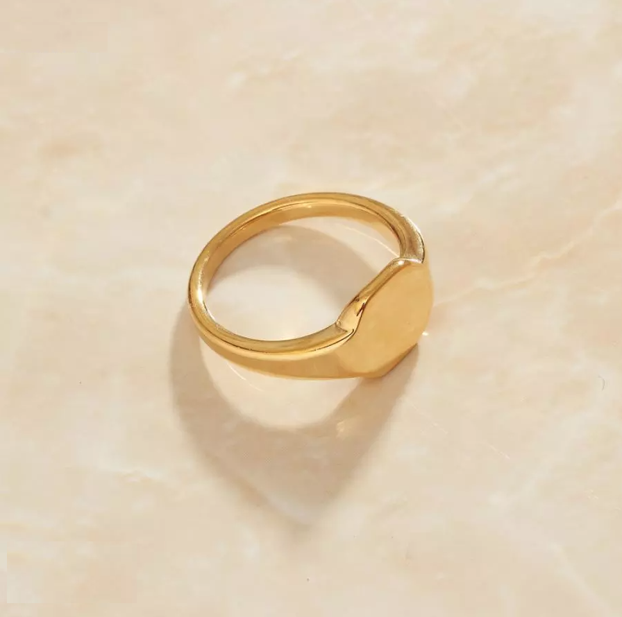 Gold Minimal Signet Ring laying on a smooth marble surface.