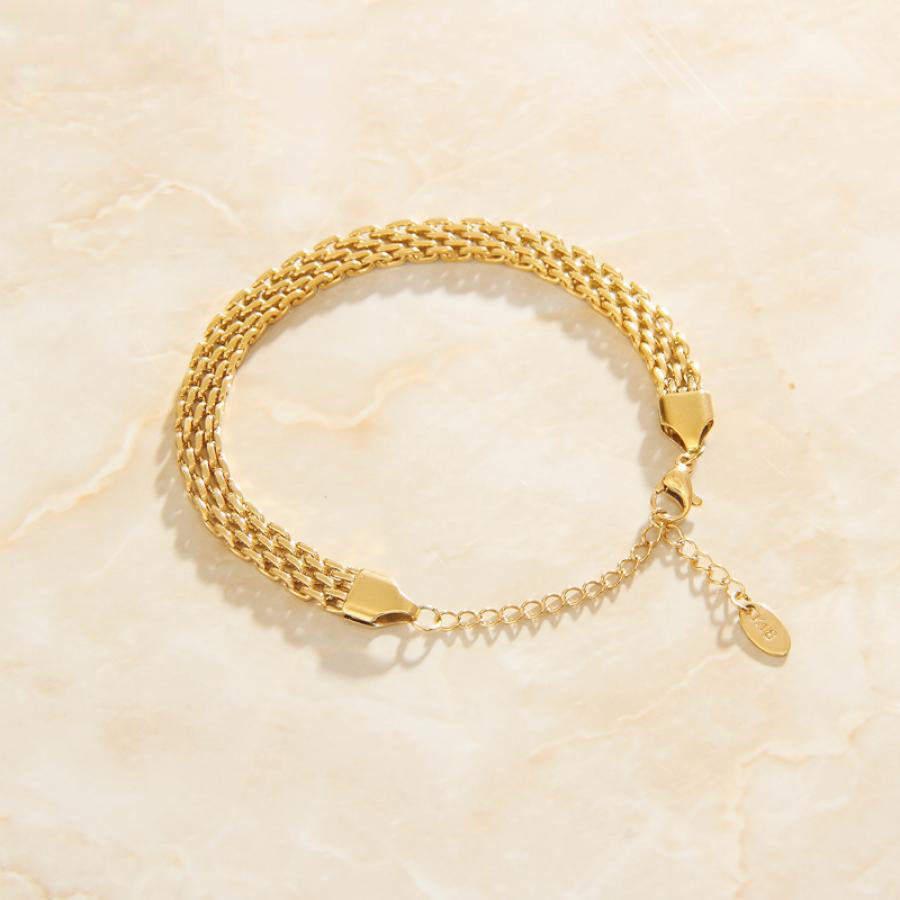 Gold Multi Layer Chain Link Bracelet on a smooth quartz surface.