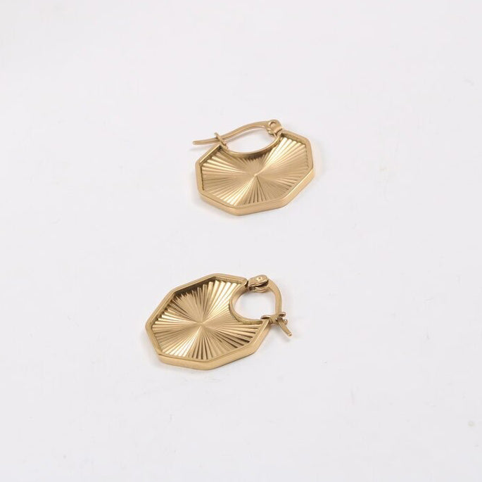 Gold Octagon Sun Earrings laying on a smooth white surface.