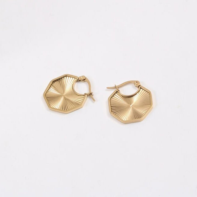 Gold Octagon Sun Earrings laying on a smooth white surface.