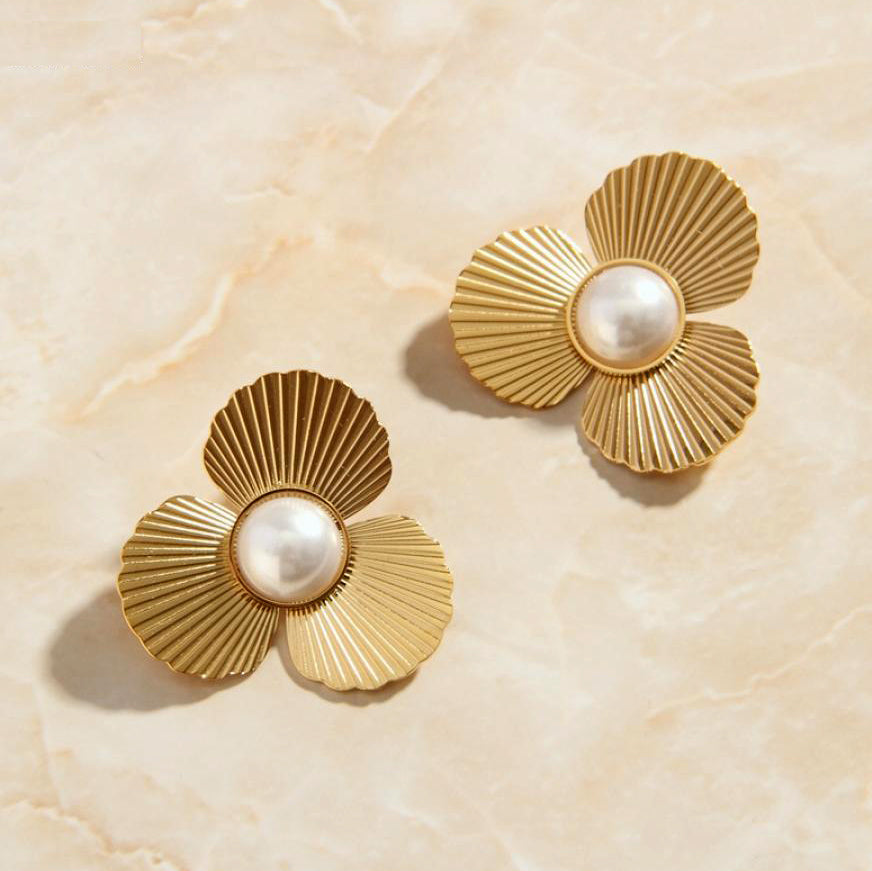 Gold Pearl Flower Earrings laying on a smooth rose quartz surface shining brightly.