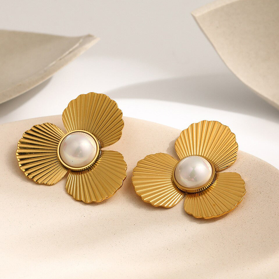 Gold Pearl Flower Earrings laying on a smooth ceramic surface.
