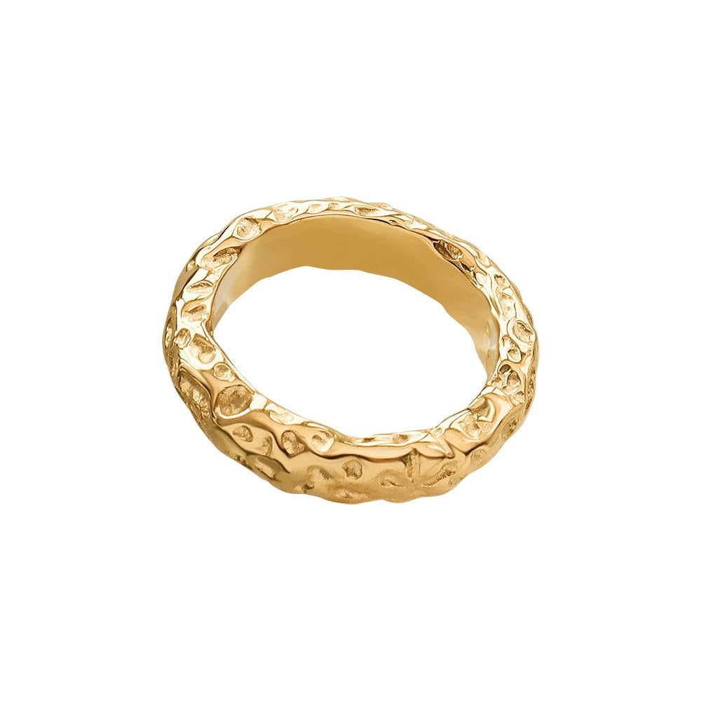 A closeup of a gold ring with a stone pattern on a white pattern,