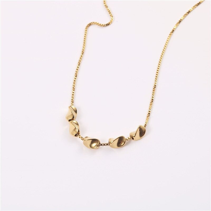 A beautiful Gold Pistachio Boxchain Necklace shining brightly over a white background.