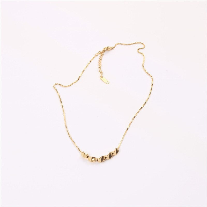 A wide shot of the Gold Pistachio Boxchain Necklace laid on a white background.