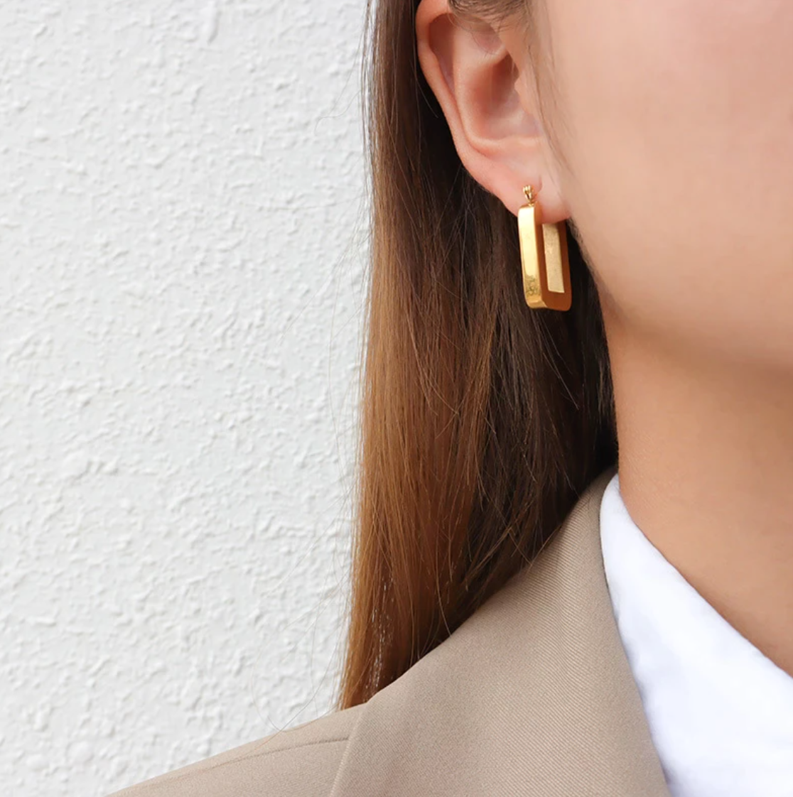 Gold Rectangular You Earrings being worn by a woman with dark hair.