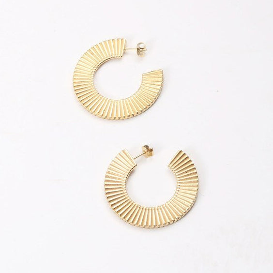 Gold Ribbed Curved Earrings on a smooth white surface.