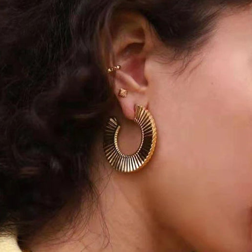 Gold Ribbed Curved Earrings worn by a beautiful woman with dark brown hair.