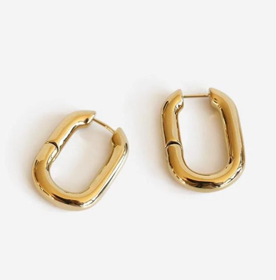 Gold Rounded Oval Earrings laying on a smooth white surface.