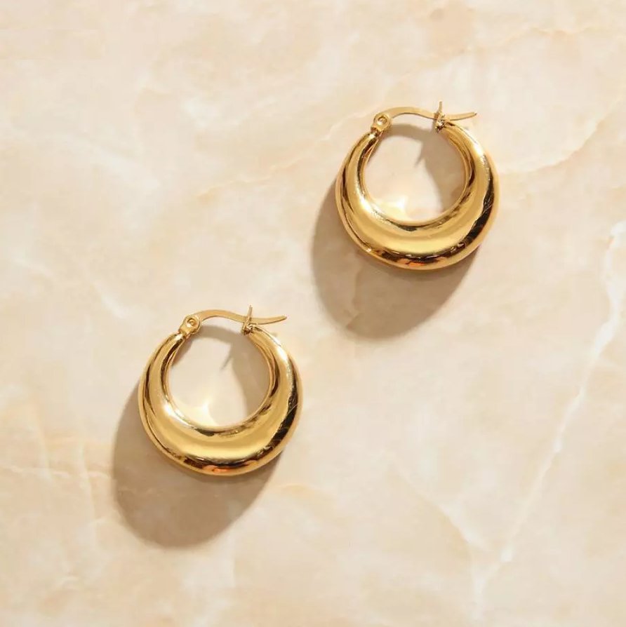 Overhead photograph of Gold Smooth Curved Earrings laying on a rose quartz surface.